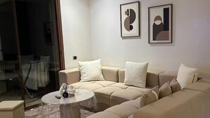 A living room with a beige sectional sofa, a small round coffee table, and two framed artworks on the wall. - Comfortable apartment at Vizir Center Parc (Marrakech)