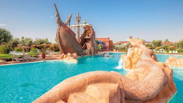 A swimming pool with a large rock formation and a shipwreck structure. - Comfortable apartment at Vizir Center Parc (Marrakech)