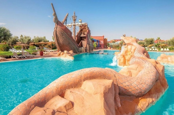 A swimming pool with a large rock formation and a shipwreck structure. - Comfortable apartment at Vizir Center Parc (Marrakech)