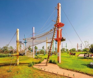 A rope bridge, wooden poles, and a grassy area with a clear sky. - Comfortable apartment at Vizir Center Parc (Marrakech)