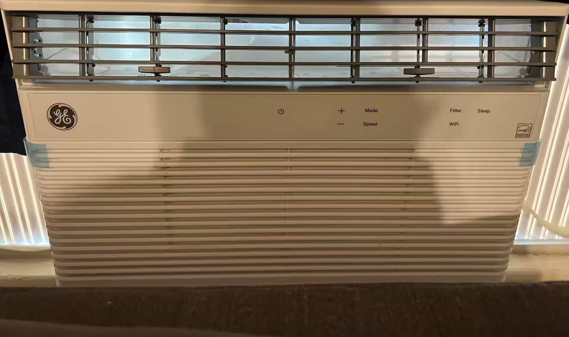 Eine GE Klimaanlage mit Bedienfeld für Power, Modus, Geschwindigkeit, WLAN und Schlafmodus.