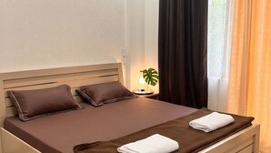 A neatly made bed with pillows, a bedside lamp, and a plant.