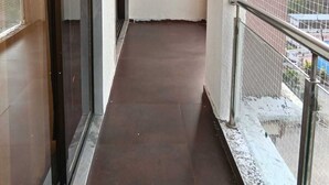 A corridor with a metal railing, a window with a metal grille, and a door with a metal handle.