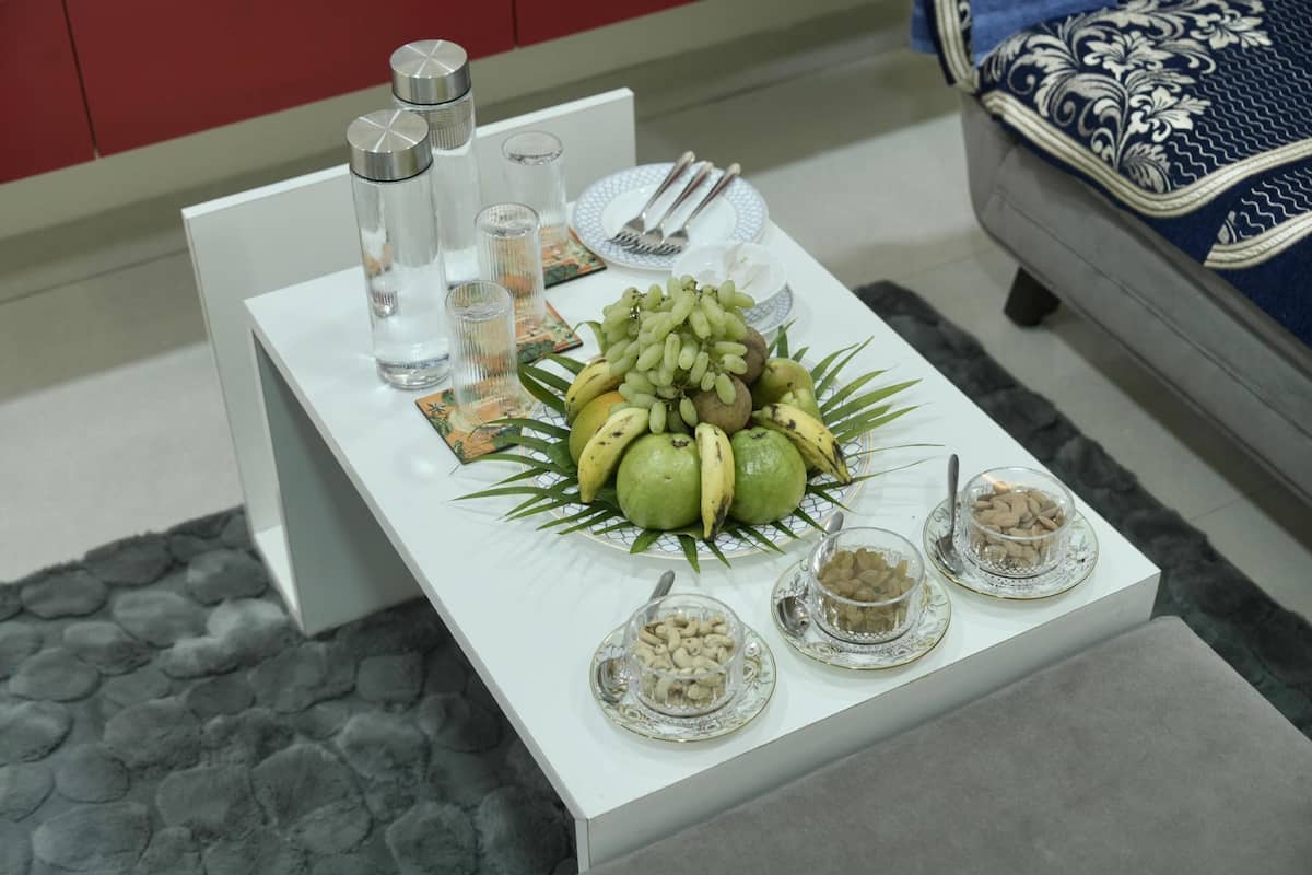 A dining table with a fruit centerpiece, glassware, and a plate with cutlery.