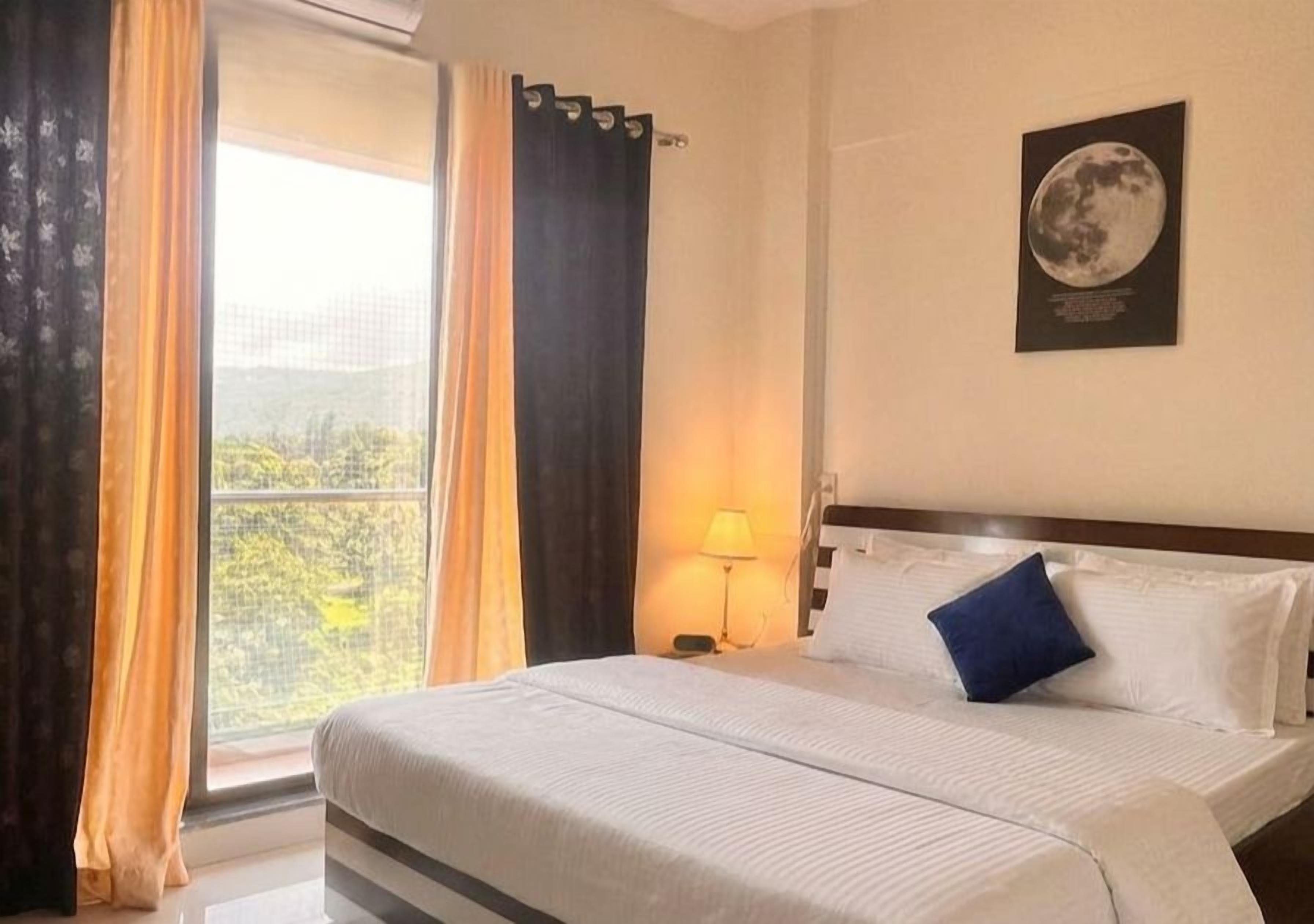 Une chambre d’hôtel avec un lit, une table de chevet, une lampe et une fenêtre avec des rideaux.