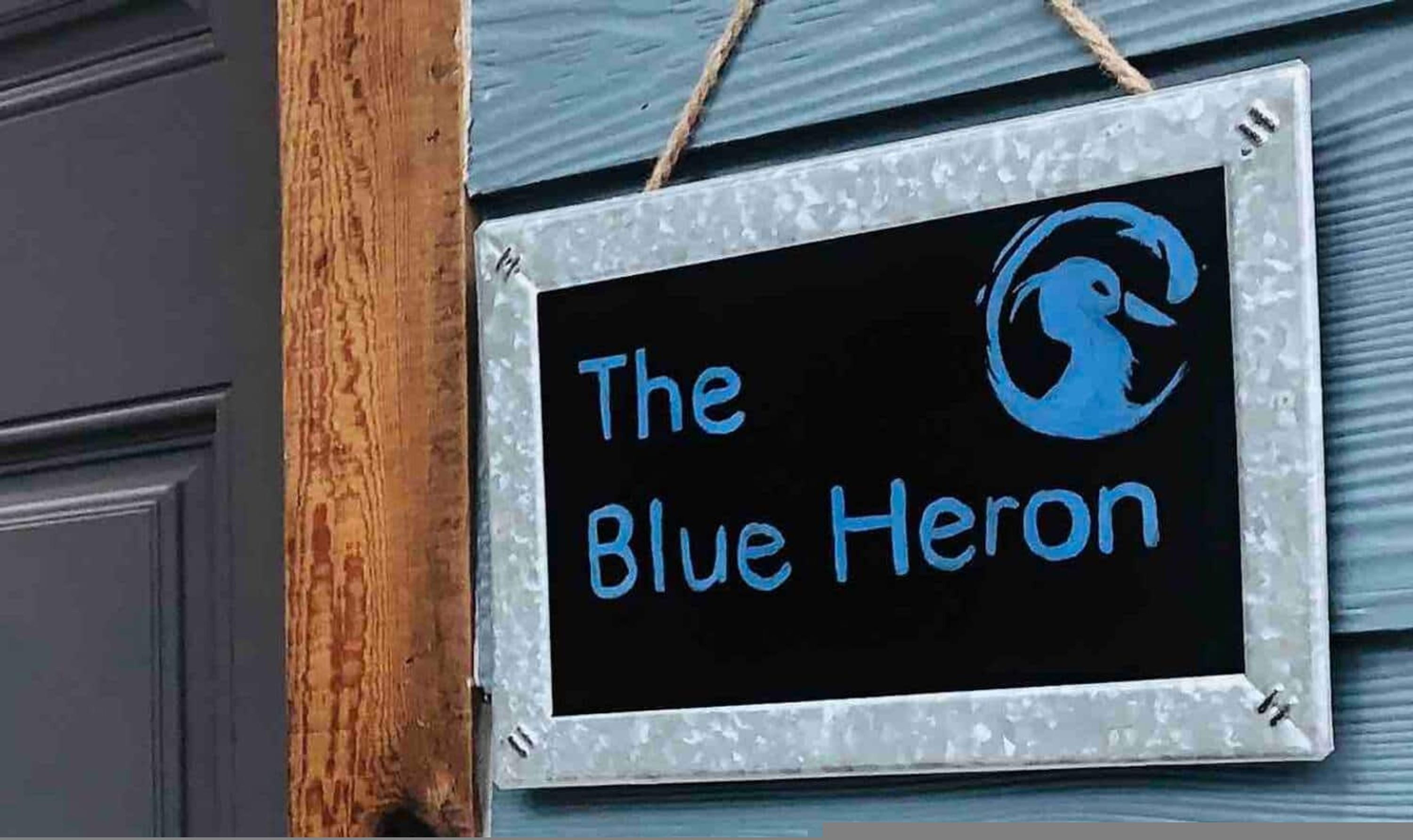 Een bord met de tekst 'The Blue Heron' en een blauw logo.