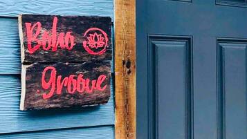Une enseigne en bois avec du texte rouge sur une porte bleue.