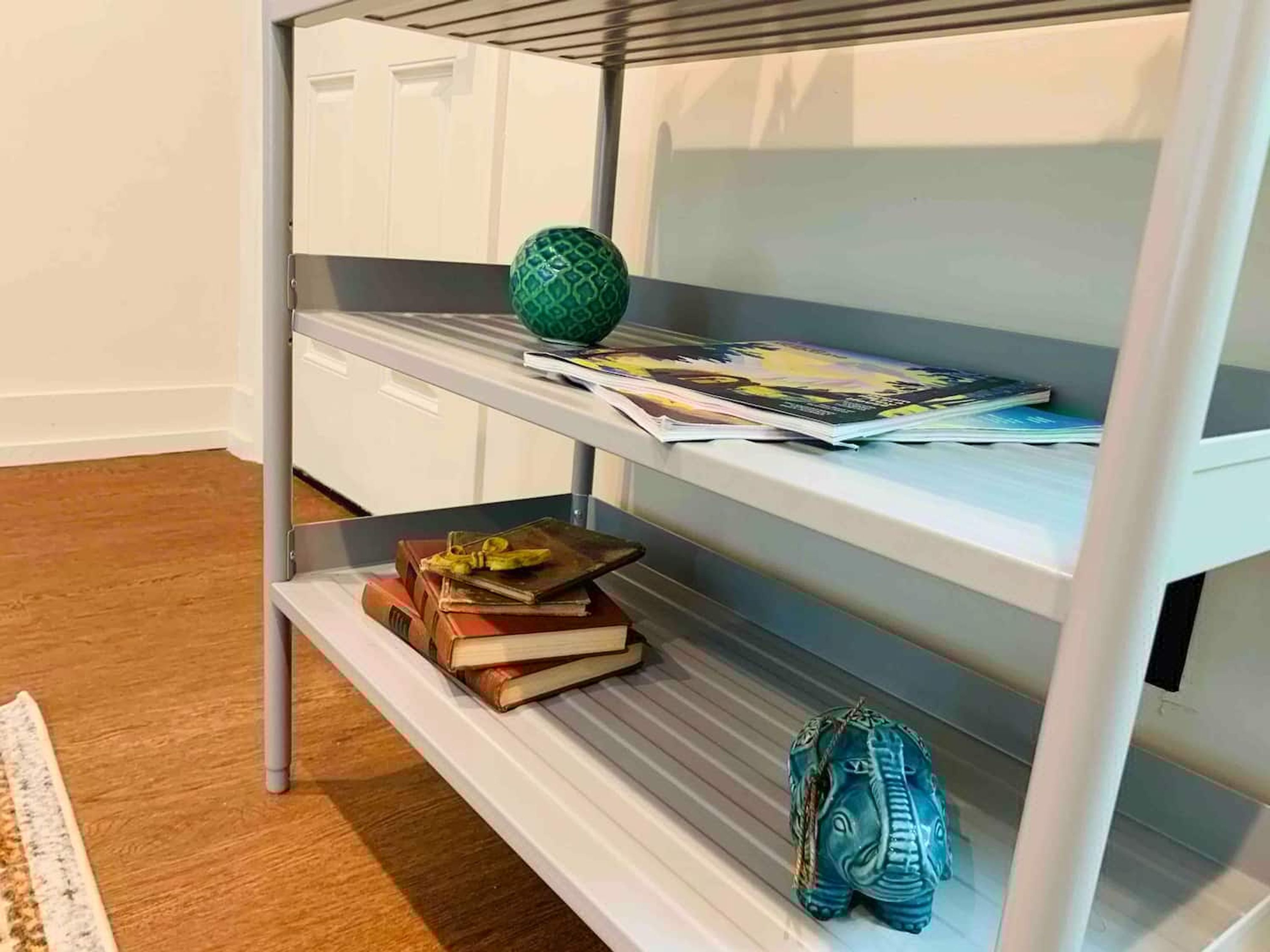 Una estantería metálica con libros, una esfera decorativa y una figurita.