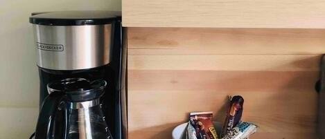 Eine Kaffeemaschine, zwei Gläser und eine Schüssel mit Snacks auf einer Küchenarbeitsplatte.