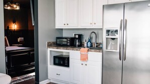 A kitchen with white cabinets, a stainless steel refrigerator, a microwave, and a coffee maker. - Moody Blues Studio Perfect for Work or Romance (Memphis)