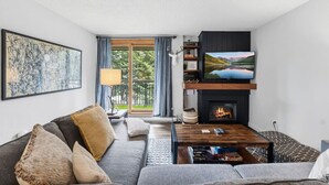 Ein Wohnzimmer mit Sofa, Couchtisch, Kamin, Fernseher und Kunstwerken.