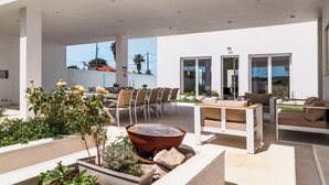 An outdoor patio with a dining area, seating, and a fire pit. - Villa Jannah -Luxury Halal Retreat (Quinta do Anjo)