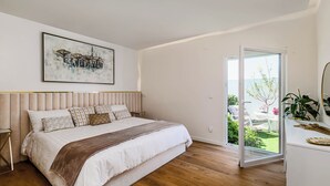 A bedroom with a bed, a bedside table, a nightstand, a window with a view of the outdoors, and a painting on the wall. - Villa Jannah -Luxury Halal Retreat (Quinta do Anjo)