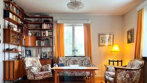 A cozy living room with a wooden floor, a floral sofa set, a wooden coffee table, a bookshelf, and a chandelier. - 7 Person Holiday Home in Virserum (Virserum)