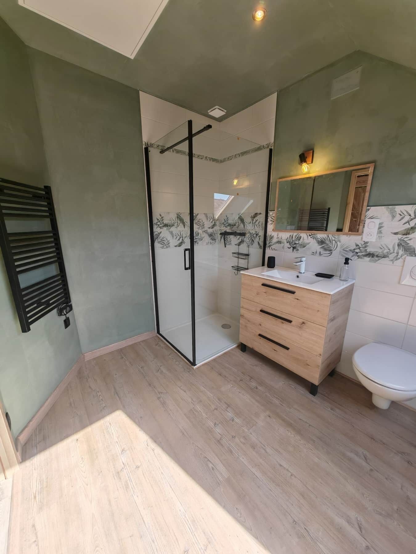 Un baño moderno con cabina de ducha de vidrio, tocador de madera y inodoro blanco.