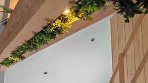 Een kamer met een schuine plafond, houten balken, een dakraam en een houten trap.