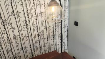 En brun soffa med en beige kudde med texten ”REVE” på, placerad framför en tapet med vertikala trädmönster.