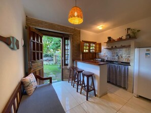 A compact kitchen with a dining area, a built-in bar, and a view of the outdoors. - Kailua apartamentos e suítes  (Ipojuca)