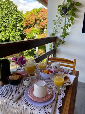 A breakfast table set with various dishes, a pitcher of orange juice, and a coffee cup. - Kailua apartamentos e suítes  (Ipojuca)