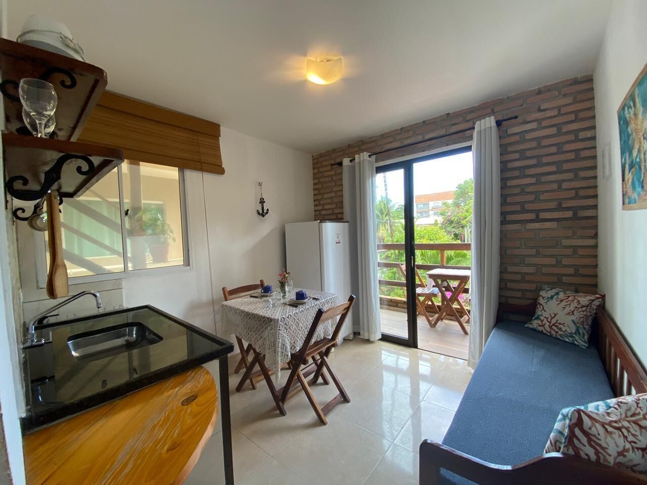 Una cocina compacta con una mesa y sillas de comedor, un sofá y un balcón con vistas.