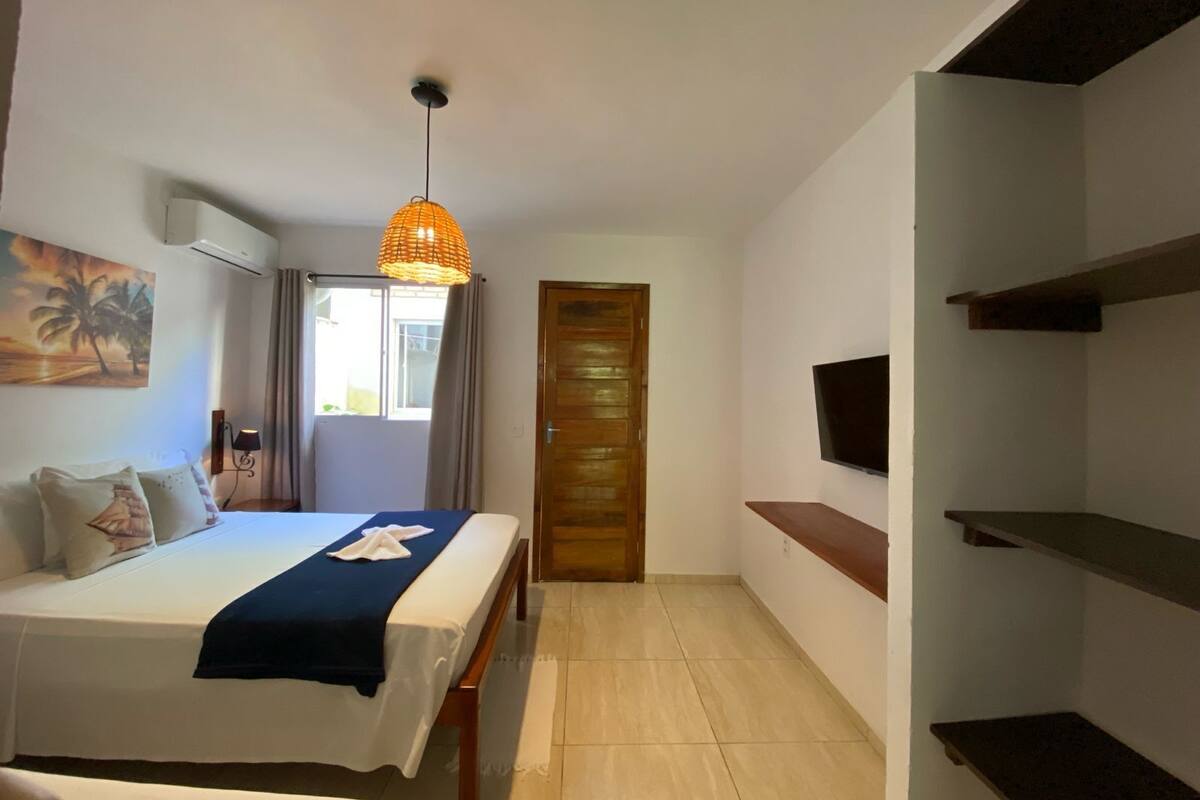 Une chambre d’hôtel avec un lit, une télévision, une porte et une fenêtre.