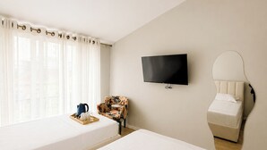A hotel room with two beds, a TV, a mirror, a coffee table, and a window with curtains. - Kein Hotel (Durres)