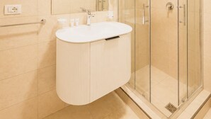 A modern bathroom with a glass shower enclosure, a white vanity with a mirror, and a wall-mounted soap dispenser. - Kein Hotel (Durres)
