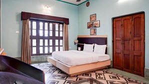 A bedroom with a bed, a wardrobe, a window with curtains, a ceiling fan, and wall-mounted lights.