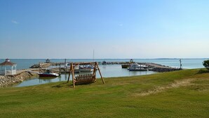 A marina with boats, a swing chair, and a gazebo. -  Marina Front 2BR Cottage #2 on Sandusky Bay — Steps from Marina, Beach & Pool (Marblehead)