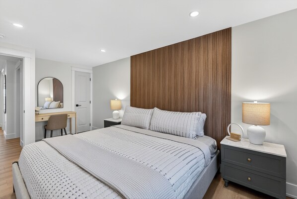 A bedroom with a bed, bedside tables, a desk, and a mirror. - Holman's Harbourview Suite -Renovated Waterview Suite in the Heart of Summerside (Summerside)