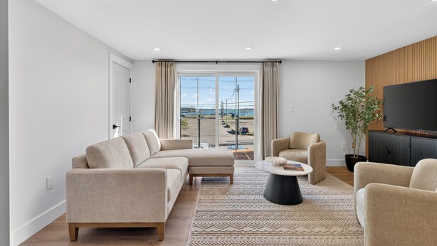 A modern living room with a sectional sofa, a coffee table, and a TV. - Holman's Harbourview Suite -Renovated Waterview Suite in the Heart of Summerside (Summerside)