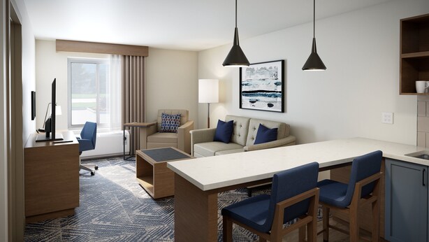 A modern hotel room with a dining area, a sofa, a chair, a desk, and a lamp. - Candlewood Suites Louisville Fair Expo Center by IHG (Louisville)