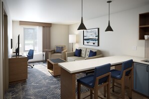 Et moderne hotelværelse med spiseplads, en sofa, en stol, et skrivebord og en lampe.