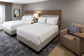 A hotel room with two beds, a nightstand, a lamp, a sofa, and a patterned rug. - Candlewood Suites Louisville Fair Expo Center by IHG (Louisville)