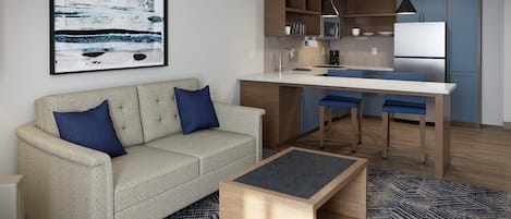 Un salon moderne comprenant un canapé, une table basse et un coin cuisine avec une table à manger et des chaises.