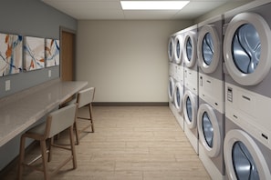 A laundry room with multiple washing machines, a wooden bench, and abstract art on the wall. - Candlewood Suites Louisville Fair Expo Center by IHG (Louisville)