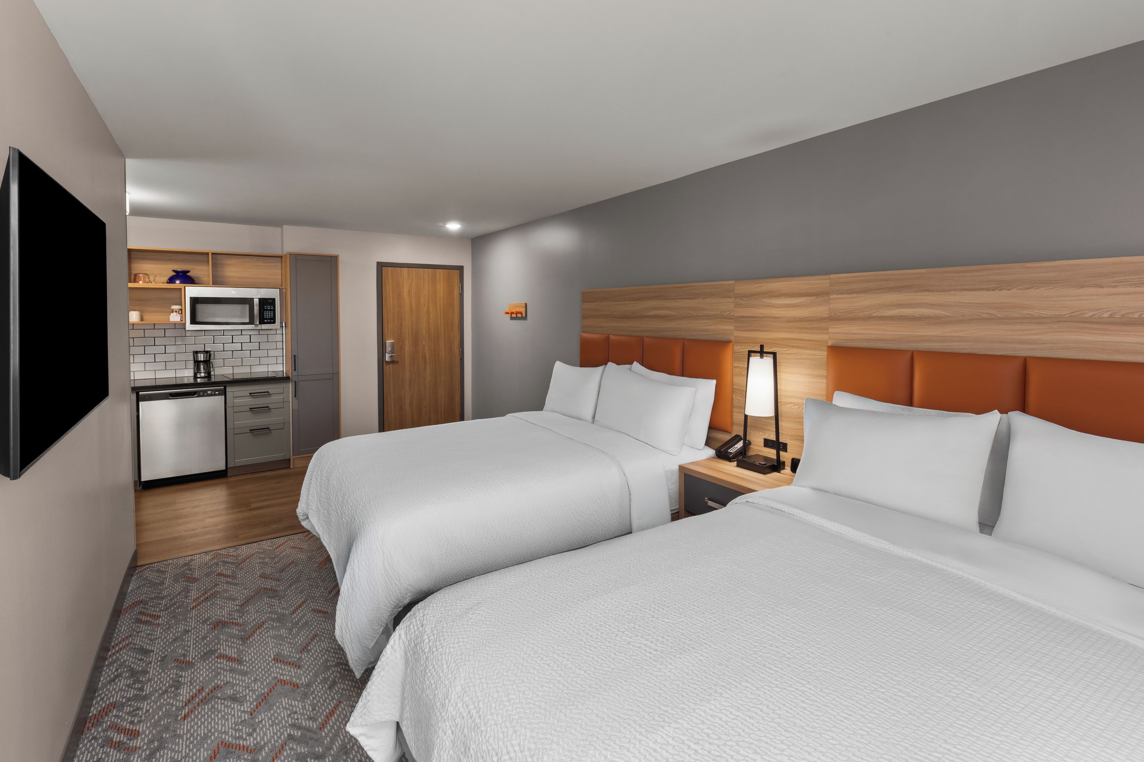 Una habitación de hotel con dos camas, una kitchenette y una televisión.