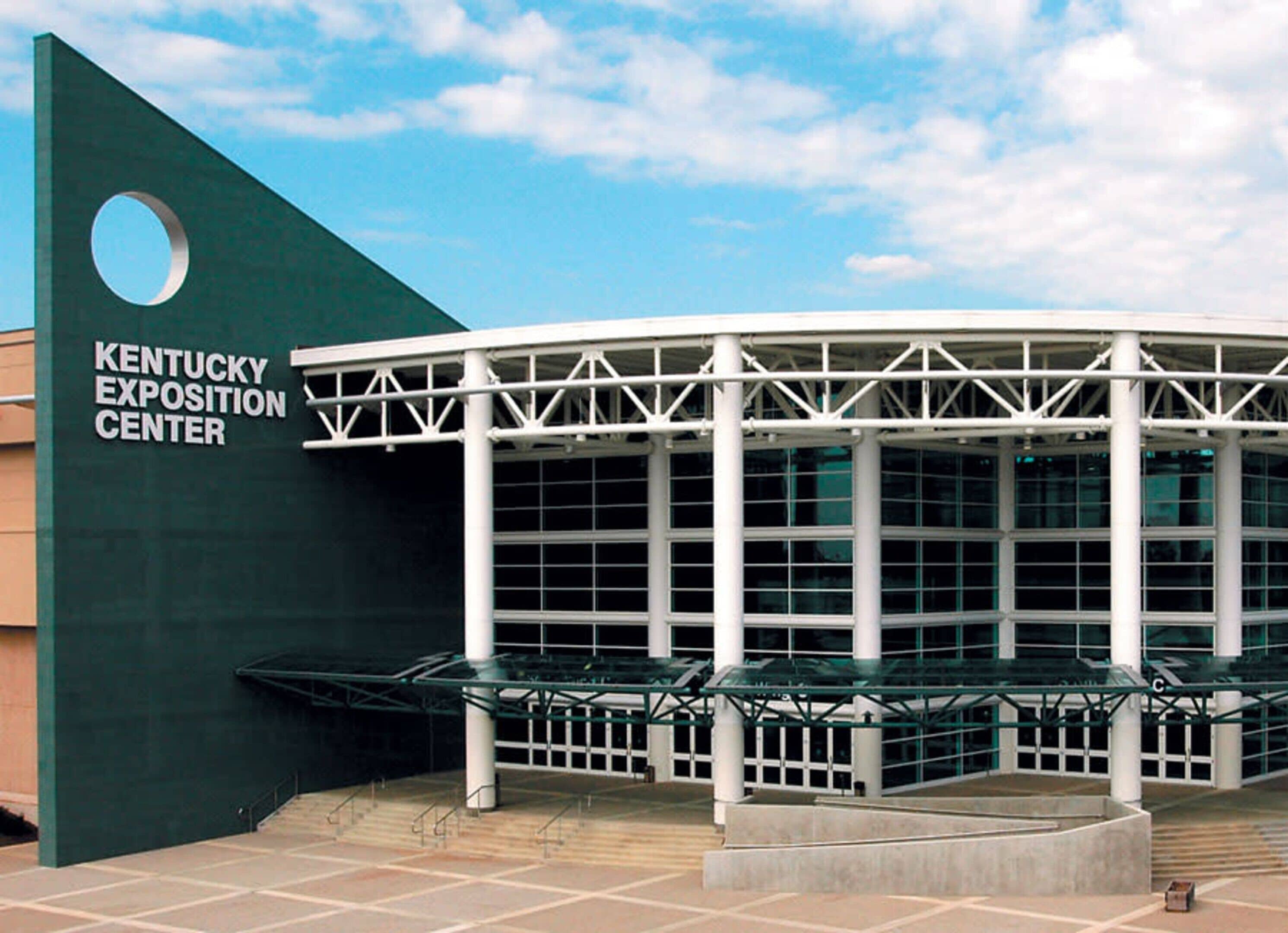 The Kentucky Exposition Center's exterior with a large glass facade and a distinctive green and white color scheme.