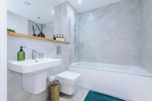 A modern bathroom with a white sink, toilet, and bathtub. - Stylish Family Retreat In Heart of Leeds City Centre (Leeds)