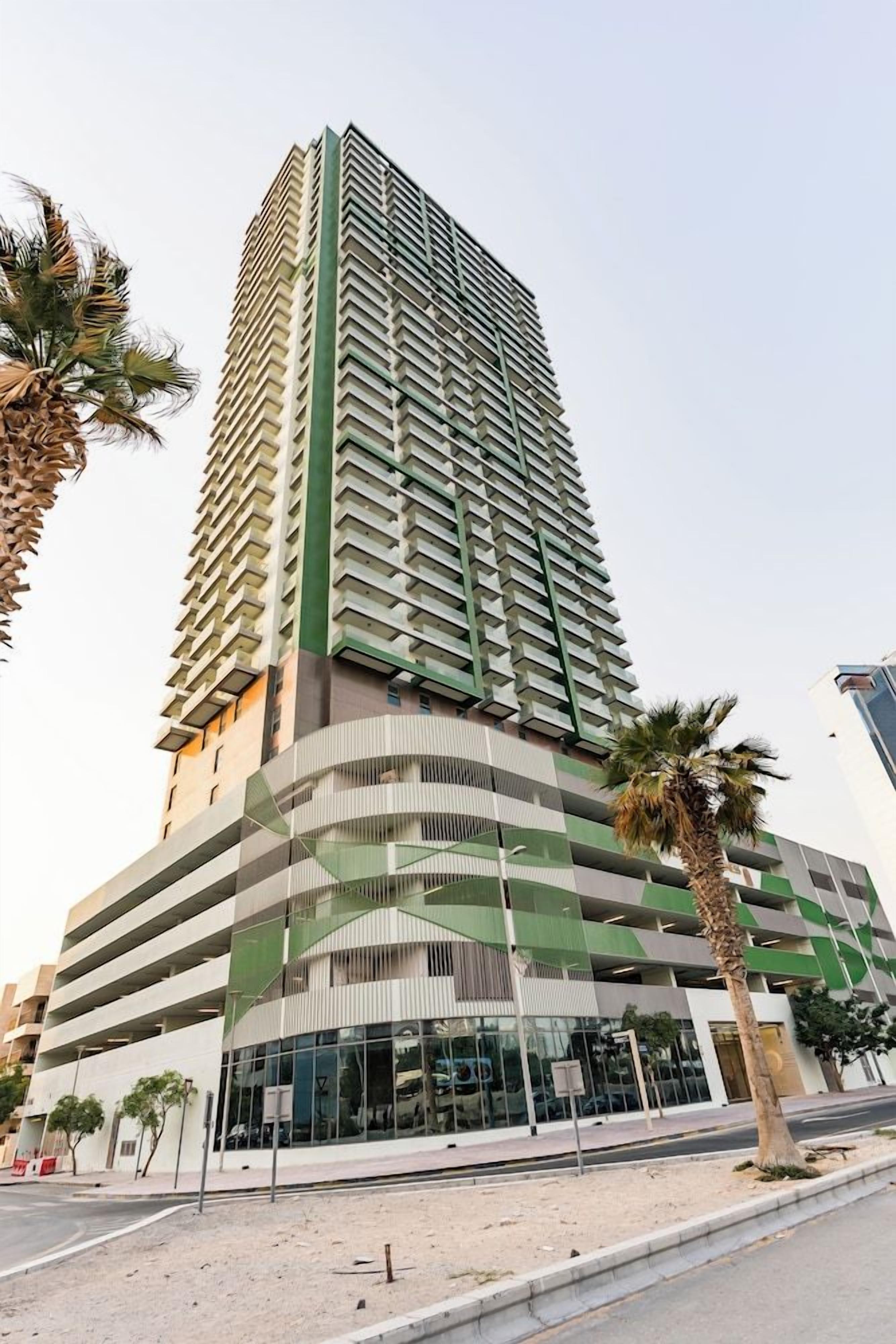 A high-rise building with a modern design, featuring a prominent green and white color scheme, and a series of balconies.