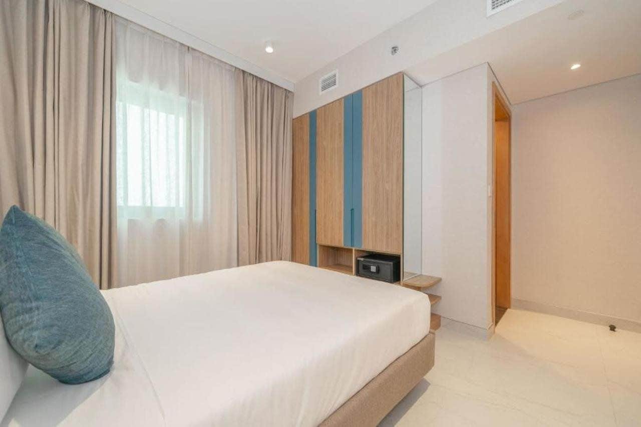 A bedroom with a bed, a wardrobe, a mirror, and a window with curtains.