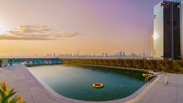 A rooftop pool with clear views of a city skyline during sunset.