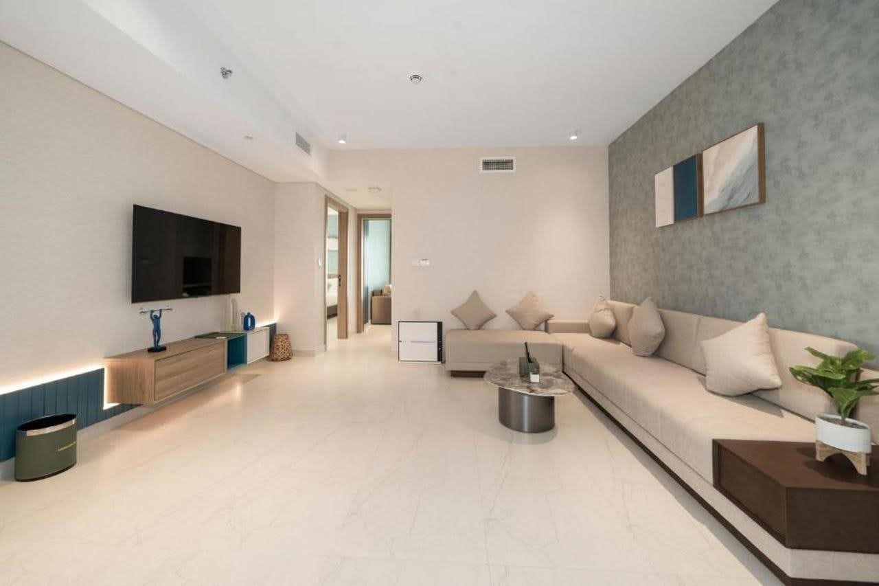 A modern living room with a flat-screen TV, a sofa, a coffee table, and a minimalist design.