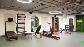 A gym with exercise equipment, a whiteboard, and a green wall.