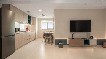 A modern kitchen with a built-in oven, a dining area with a table and chairs, and a flat-screen TV mounted on the wall.