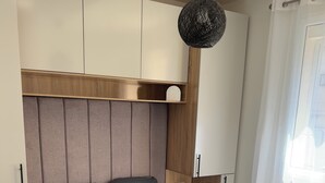 Quarto com cama, mesas de cabeceira, luminária suspensa e janela com cortinas.