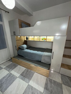 A compact room with a bed, a small desk, and a cabinet.