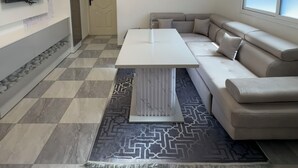 Uma sala de estar moderna com um sofá seccional, uma TV de tela plana, um tapete estampado e um lustre.