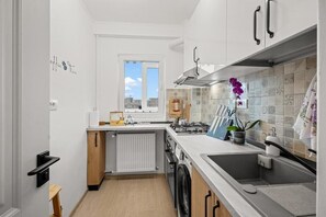 Eine kleine Küche mit Einbauofen, Spüle und Fenster.