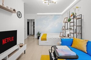 Een moderne woonkamer met een flatscreen televisie, een bank, een salontafel en een boekenplank.